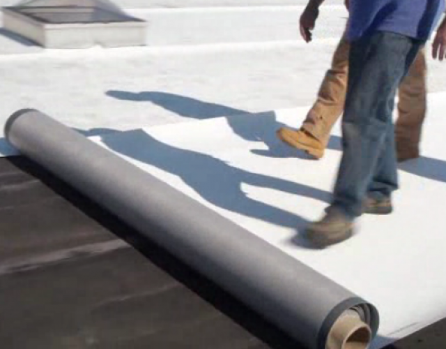 roofers rolling out single ply on flat roof