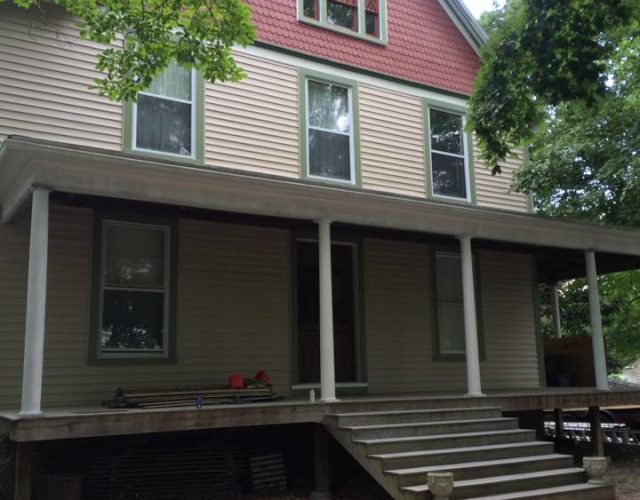 side view of historic home with completed tan and red vinyl siding